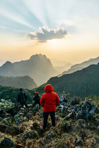 Rear view of man with mountains against sky during sunset
