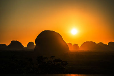 Silhouette rock formations against sky during sunset