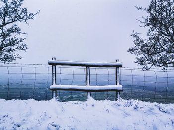 Empty bench on snow covered field during winter