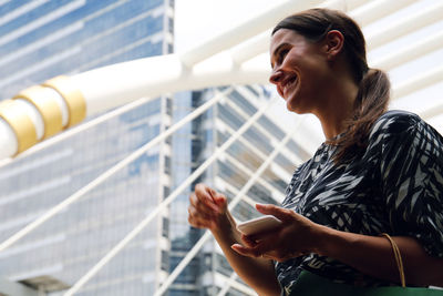 Side view of smiling young woman standing outdoors