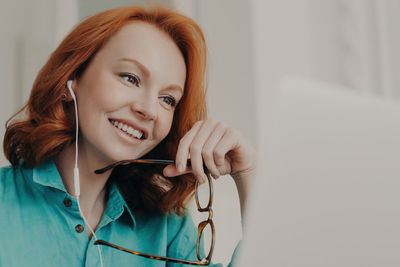 Portrait of young woman looking away against wall