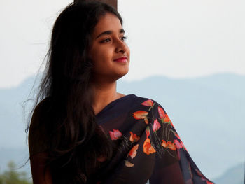 Young woman looking away against sky