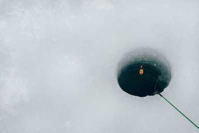 High angle view of fishing rod over hole in frozen lake