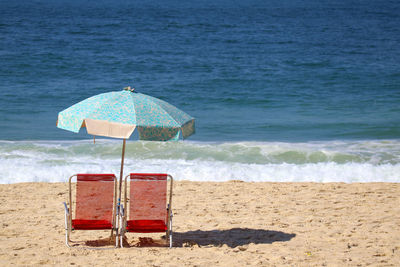 Deck chairs on beach by sea