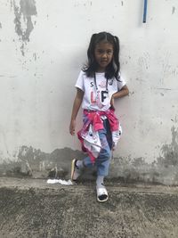 Portrait of smiling girl standing against wall