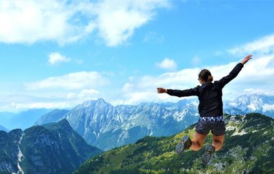 Woman jumping over mountains against sky