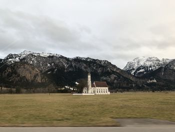 Building by snowcapped mountain against sky