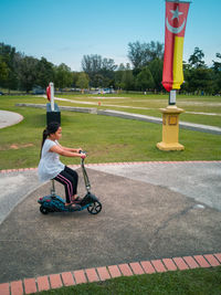 Girl riding bicycle on park against sky