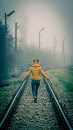 Rear view of man walking on railroad track