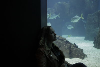 Woman looking fish in tank at aquarium