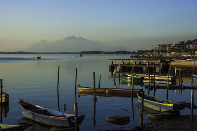 Sailboats moored at harbor against clear sky