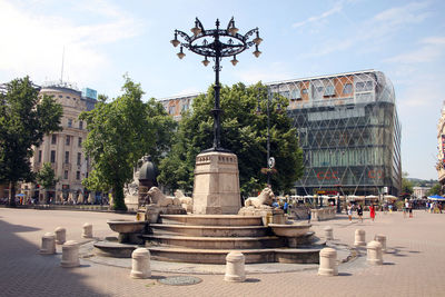 Statues on street amidst buildings against sky