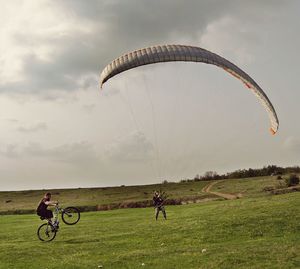 Bmx biker and paraglider on field