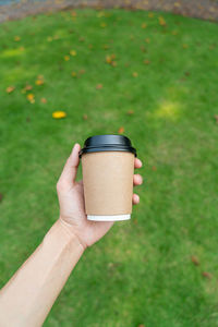 Cropped hand of woman holding coffee on field