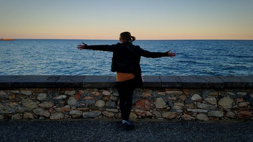 Silhouette of woman standing on beach at sunset