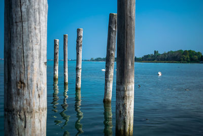 Close-up of wooden post in lake against blue sky