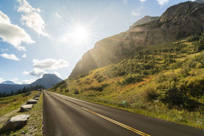 Empty road by mountains against sky