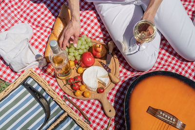 Top view of unrecognizable young woman in white pants outside having picnic, eating and playing