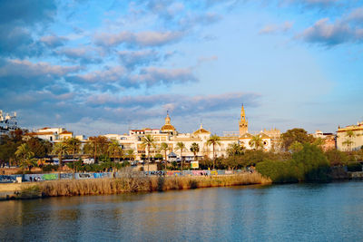 View of buildings at waterfront against cloudy sky