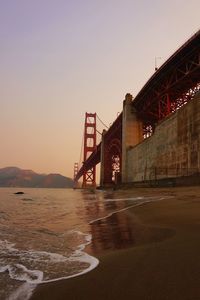 Bridge over sea against clear sky during sunset