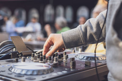 Midsection of dj using sound mixer at music concert