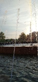 Water splashing on fountain against sky during rainy season