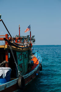 Ship moored in sea against clear blue sky