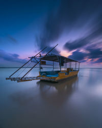 Fishing boat in sea against sky at sunset