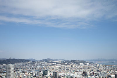 Aerial view of cityscape against blue sky