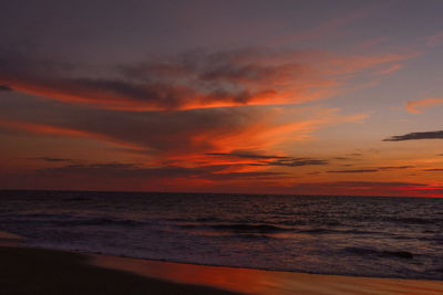 Scenic view of sea against dramatic sky during sunset