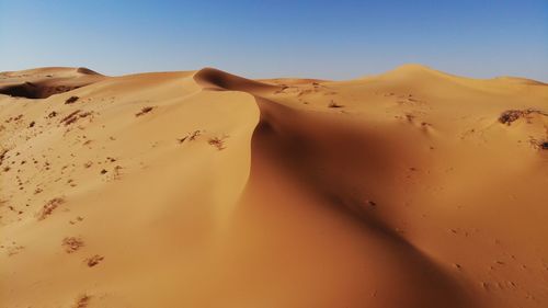 Sand dunes in desert against clear sky