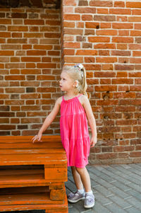 Young woman standing against brick wall