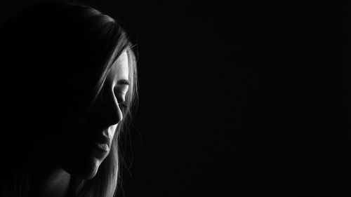 Close-up of woman against black background