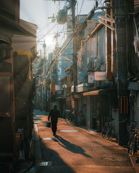 Rear view of man walking on street amidst buildings