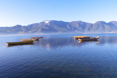 Boats on lake against clear sky