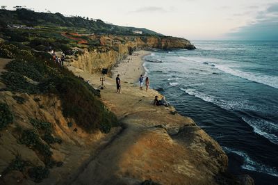 People on beach by mountain against sky