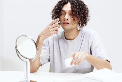 Portrait of young man applying gel on face