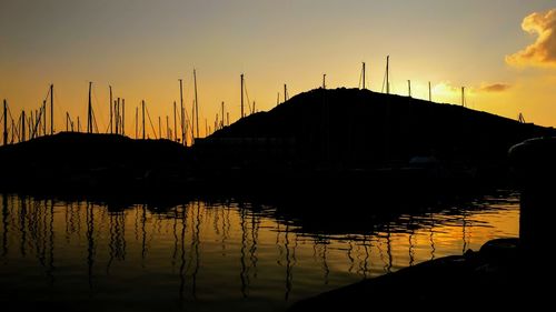 Silhouette of boats moored in water at sunset