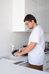 Side view of young man standing at home