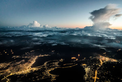 Aerial view of illuminated city against sky at sunset