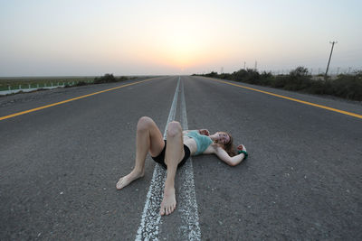 Low section of woman sitting on road