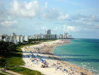 High angle view of cityscape by sea against cloudy sky