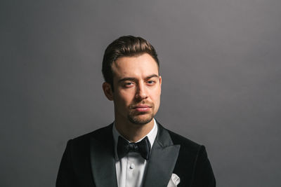Portrait of young man standing against gray background
