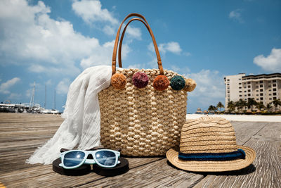 Close-up of wicker basket with hat and sunglasses on boardwalk