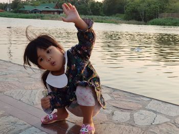 Full length of cute girl crouching by lake