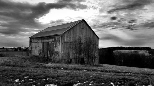 Abandoned barn on field against sky during winter