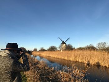 Man photographing traditional windmill on field