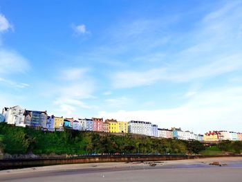 Road by buildings against blue sky
