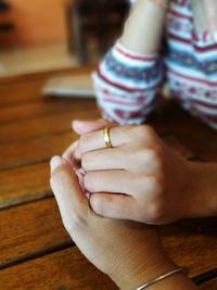 Cropped image of couple holding hands at wooden table