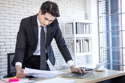 Full length of man using mobile phone at table